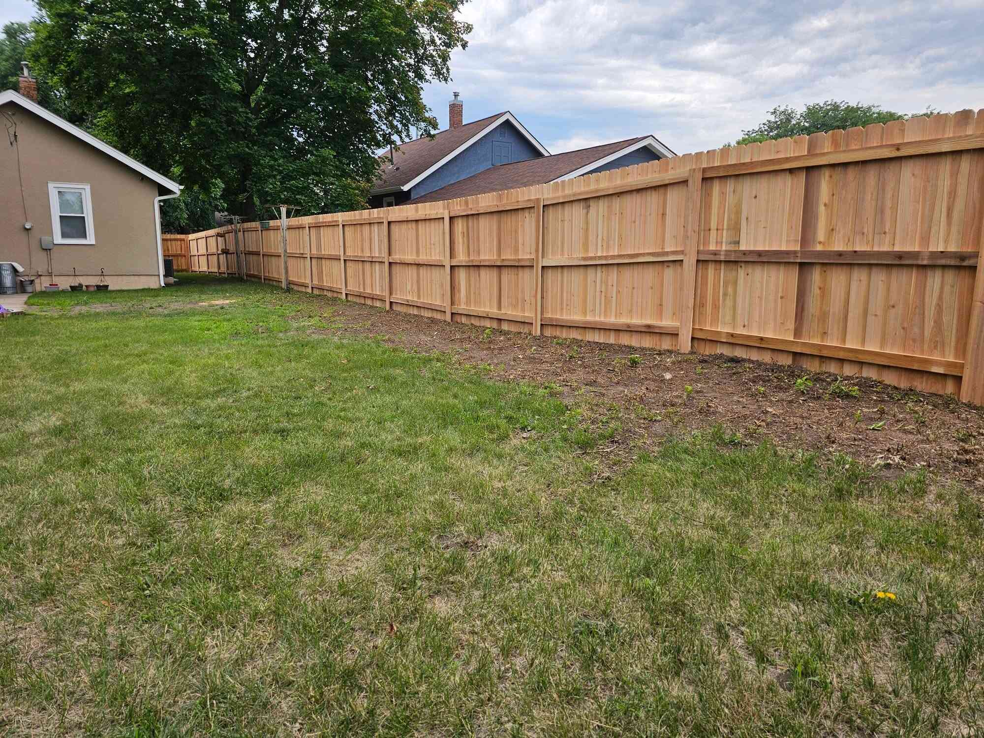 Natural cedar privacy fence, long run beside a manicured yard
