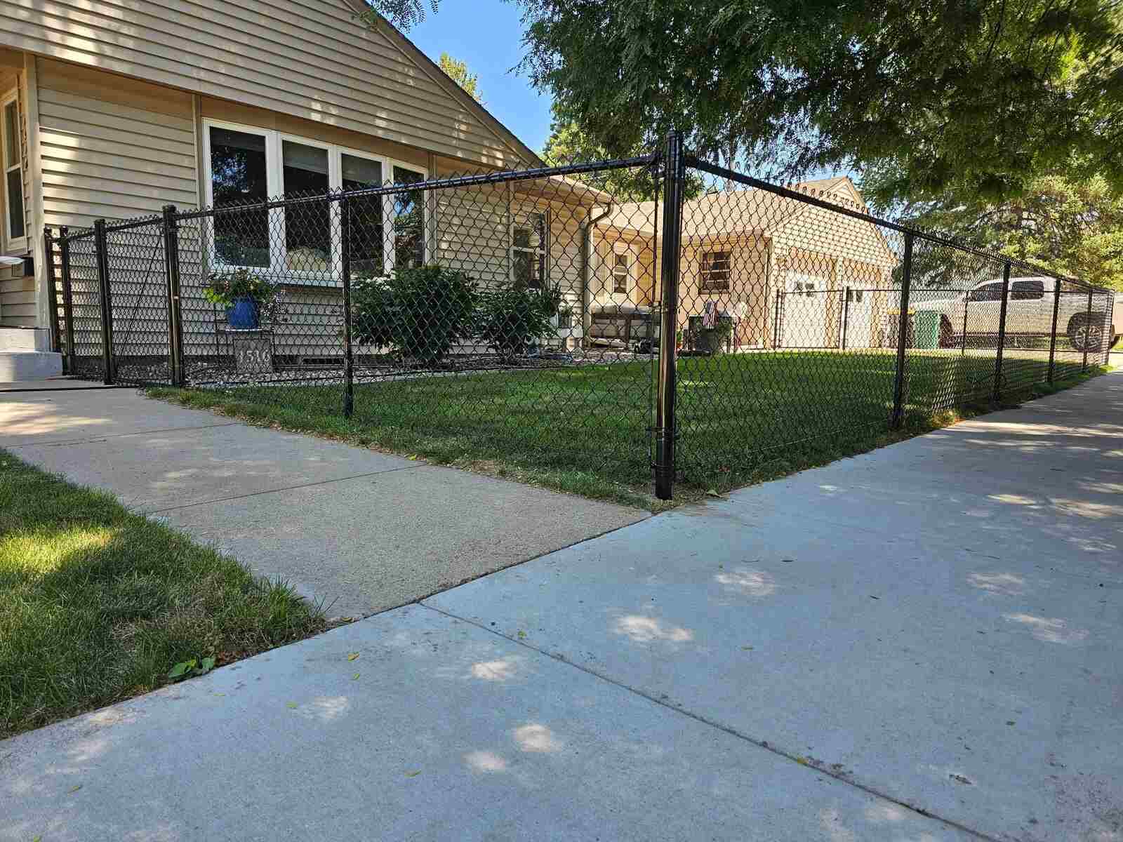 Black chain link fence with a gate in a front yard