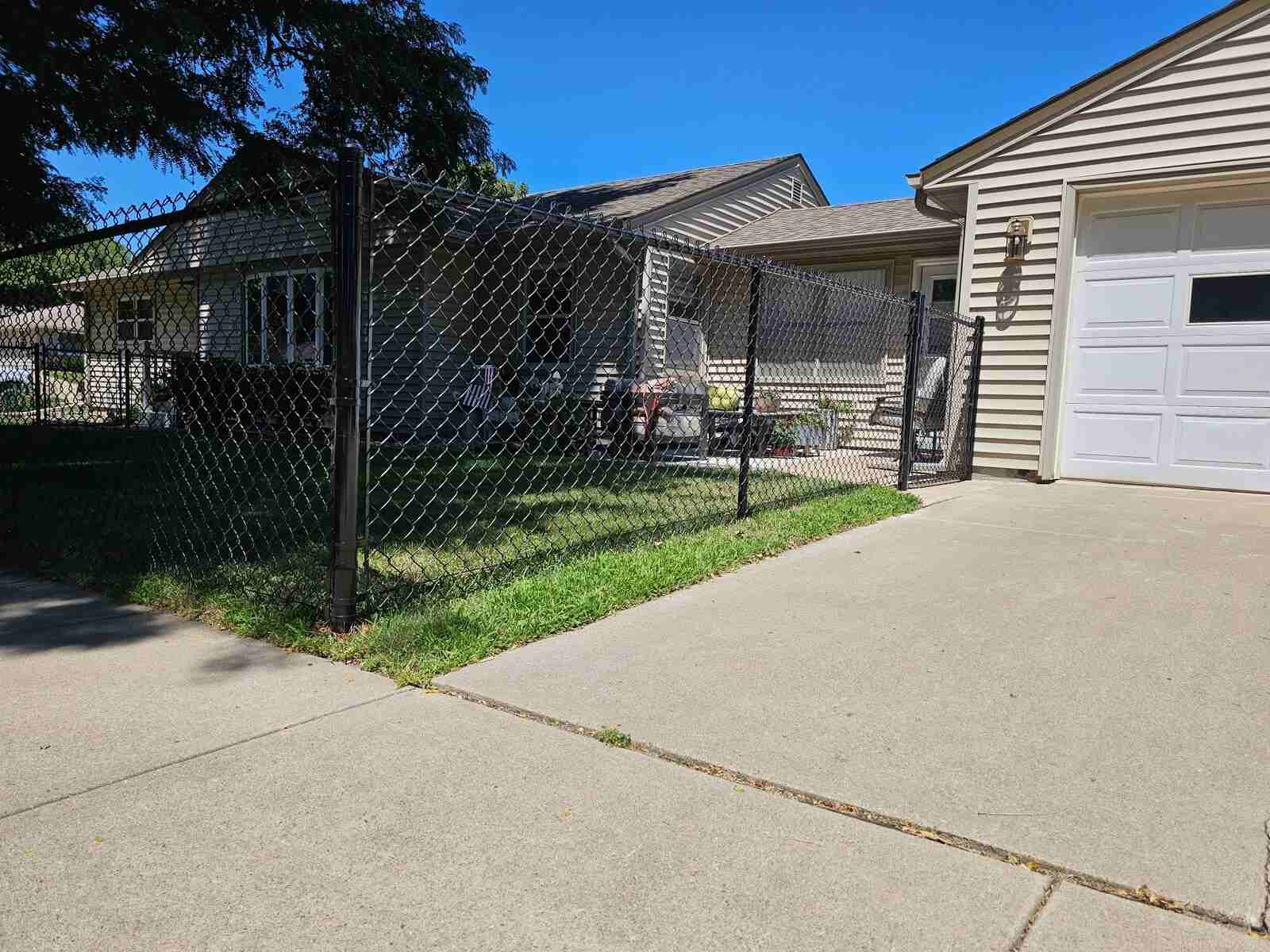 Black chain link fence along a side yard near the garage