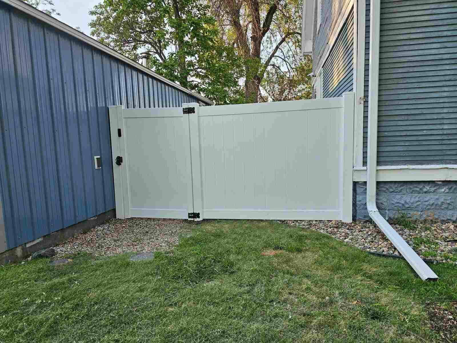 White vinyl gate detail at a metal-sided building