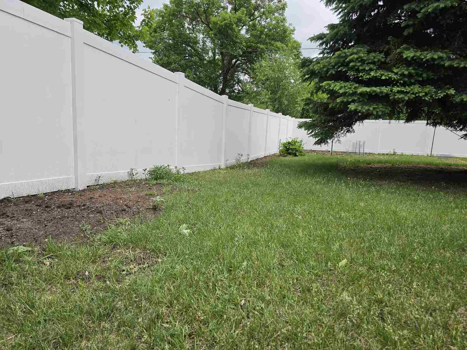 White vinyl privacy fence, straight run by the trees