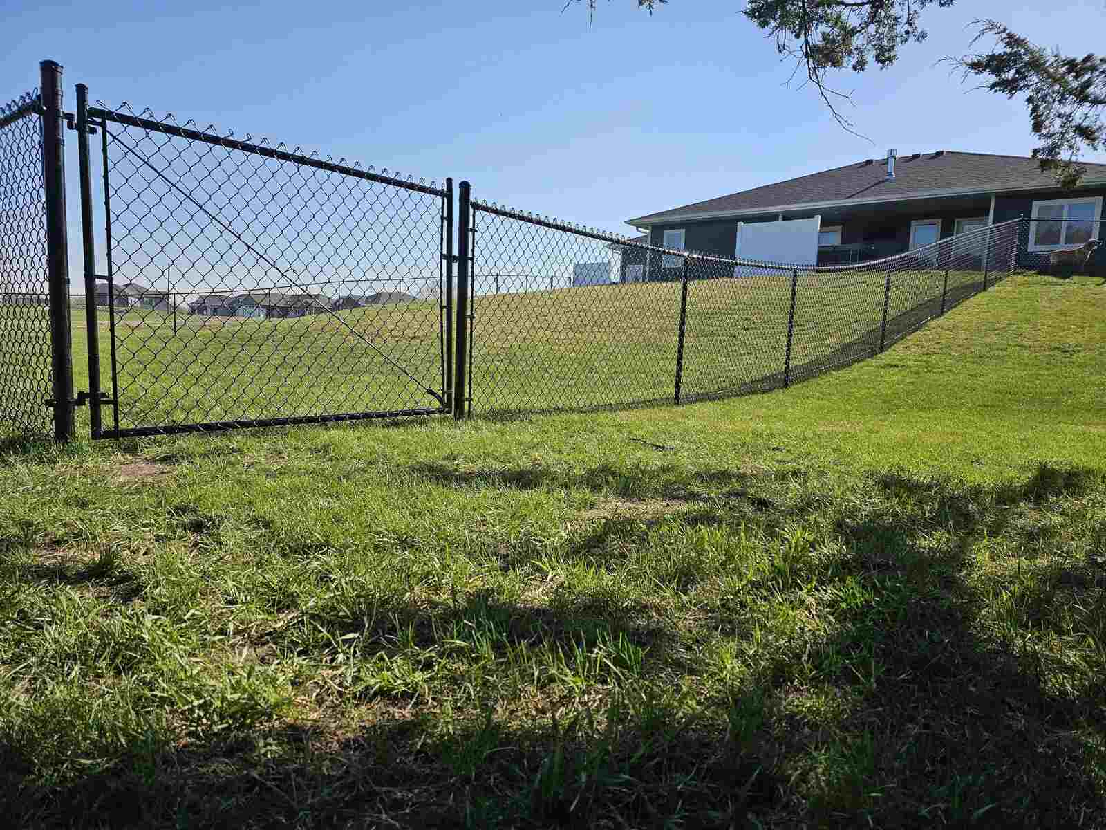 Black chain link fence with a gate on open ground