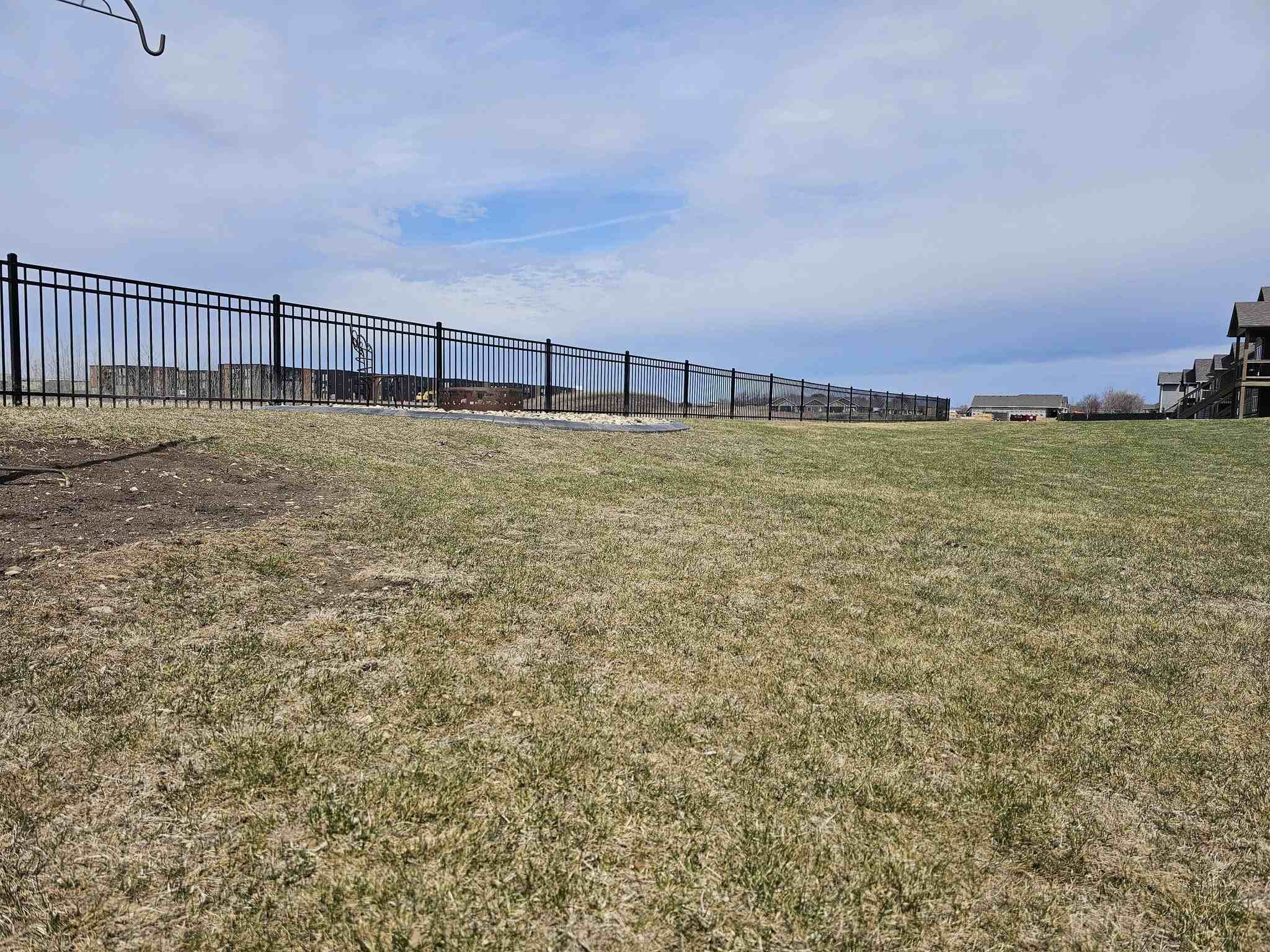 Black ornamental iron fence line along open grass