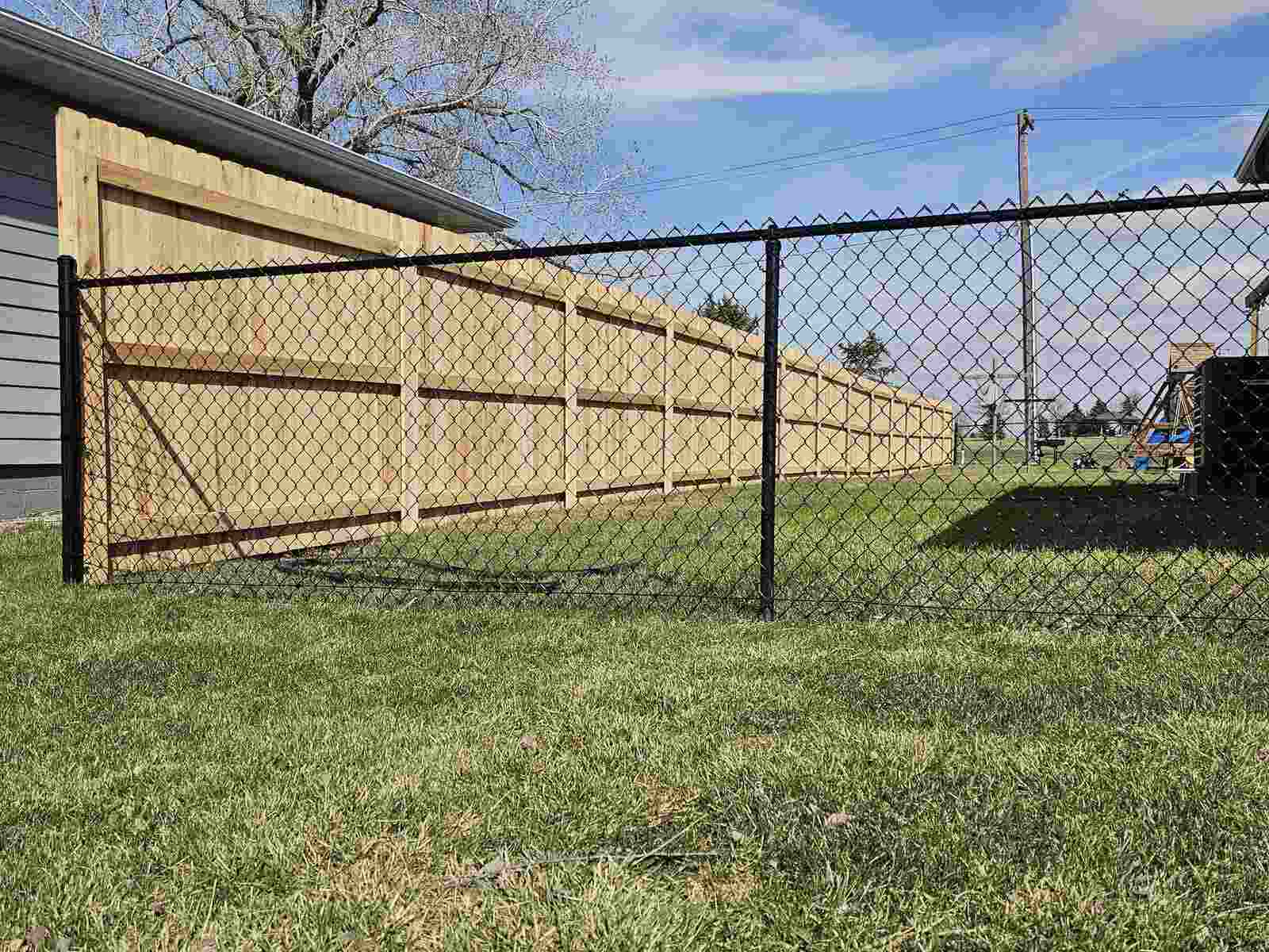 Black chain link line with a cedar privacy fence and playset behind