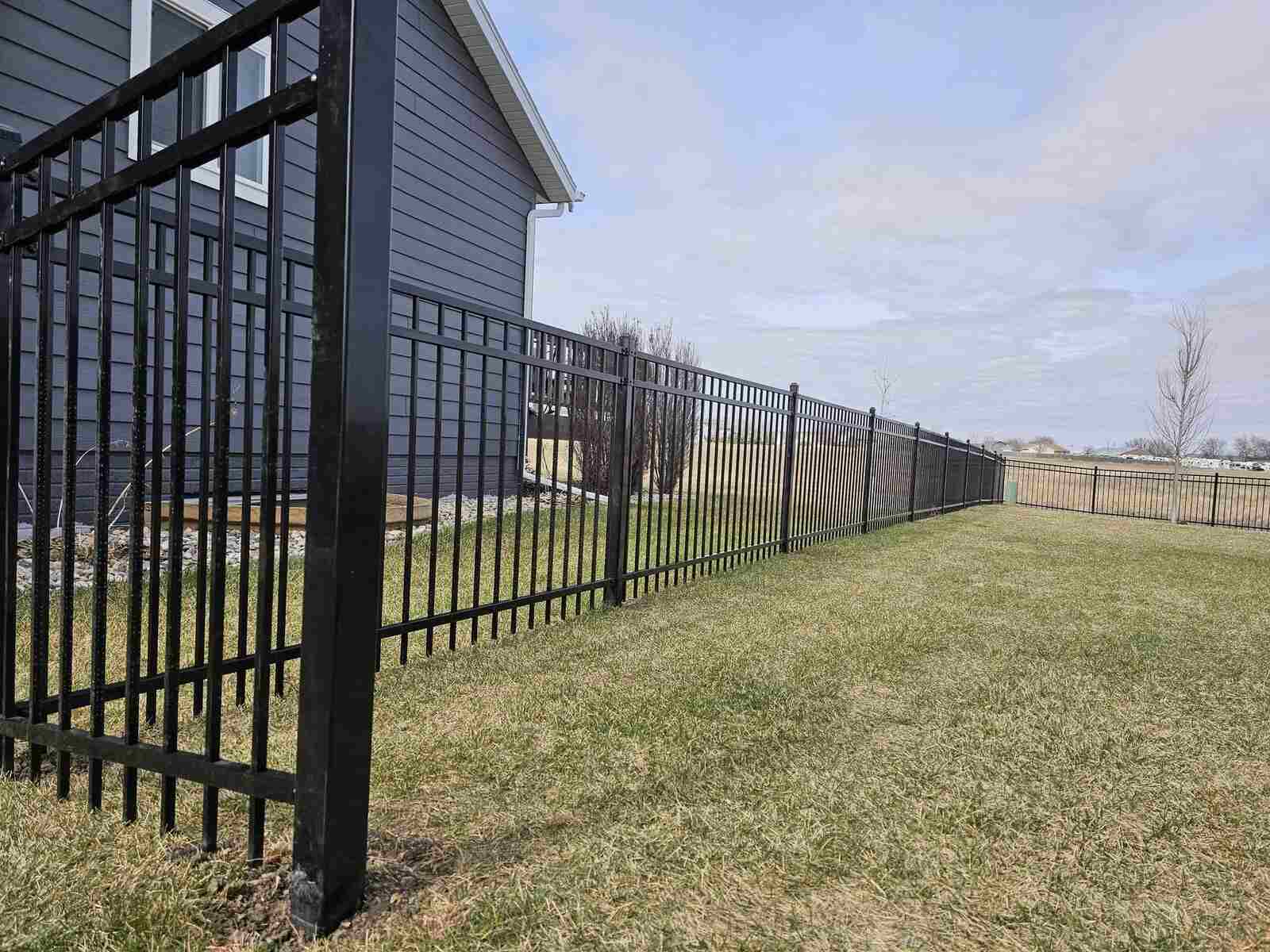 Black ornamental iron fence close to a house