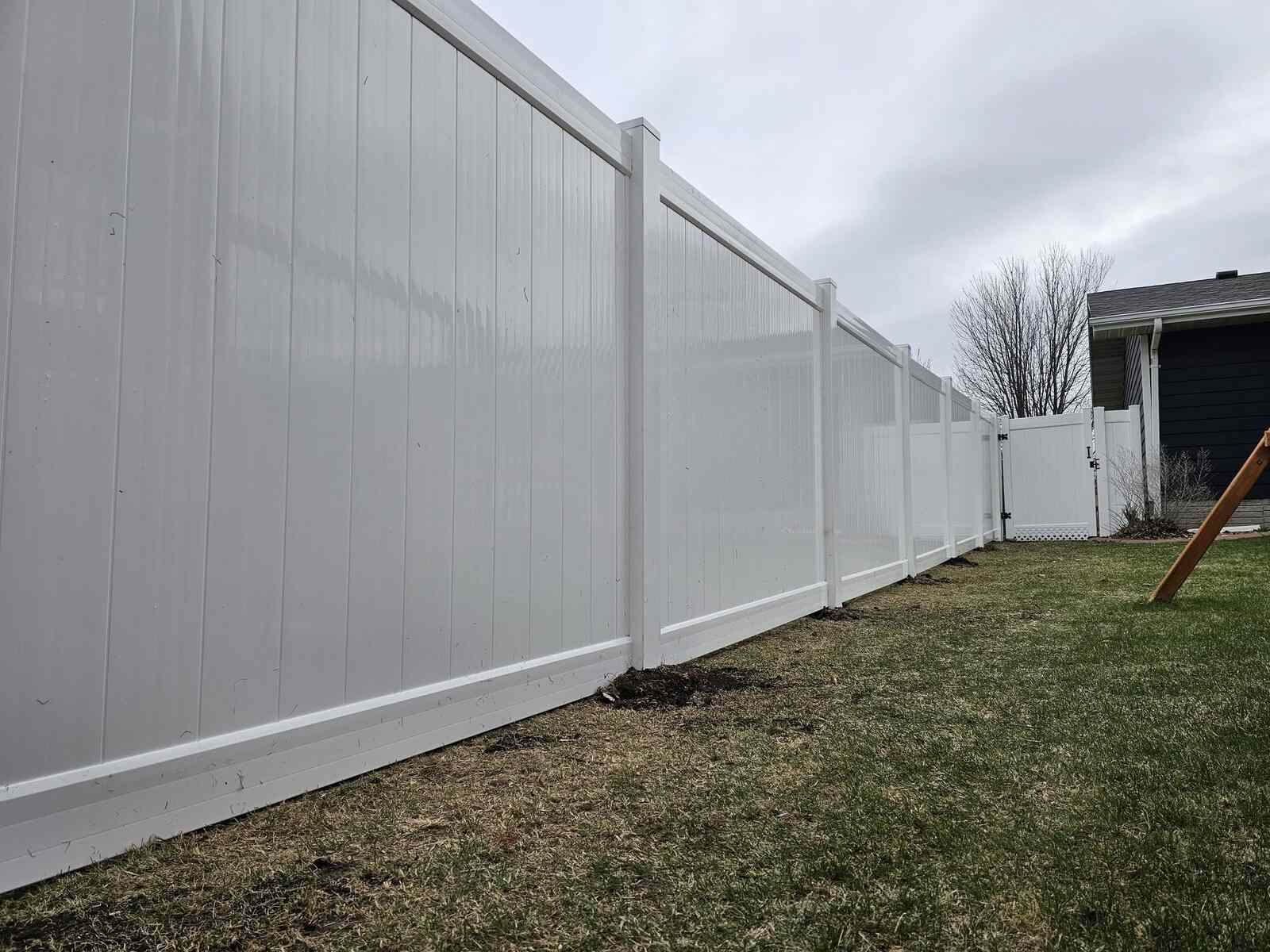White vinyl privacy fence under a cloudy sky