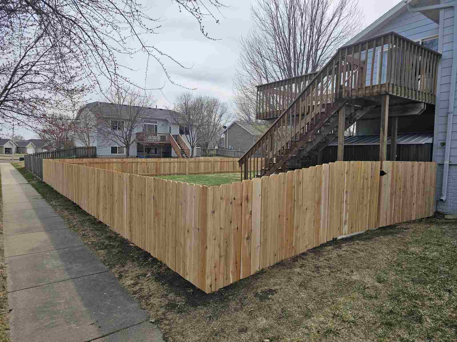 Cedar privacy fence turning a sidewalk corner, deck behind