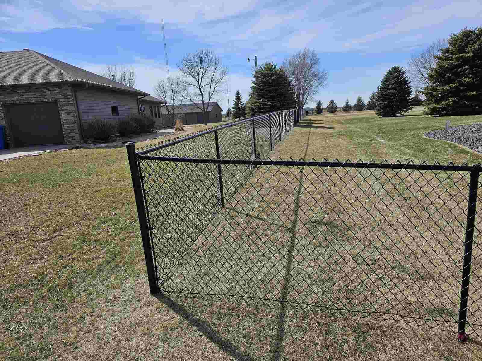Black chain link fence in front of a stone house