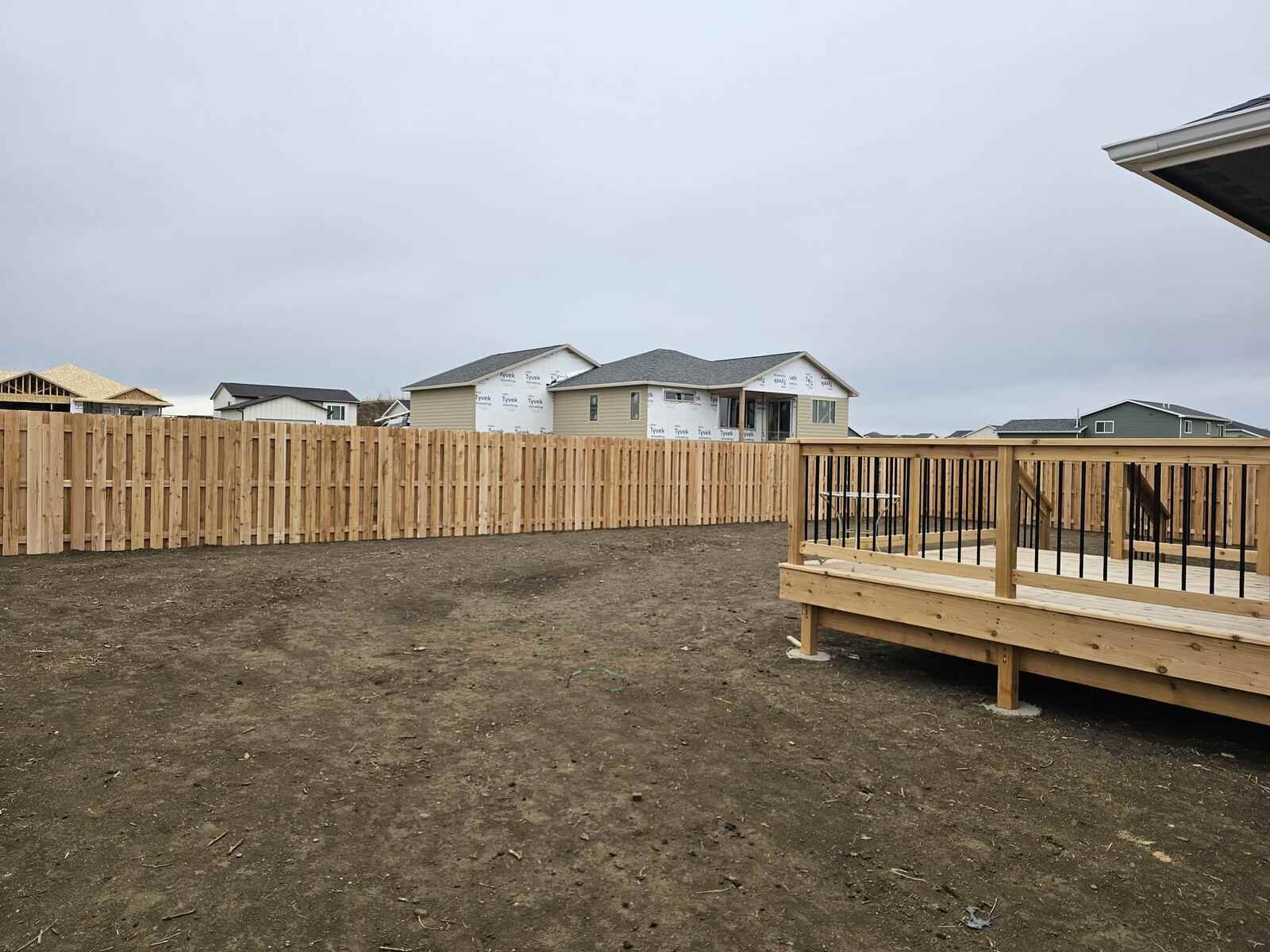 Cedar picket fence corner with a deck behind